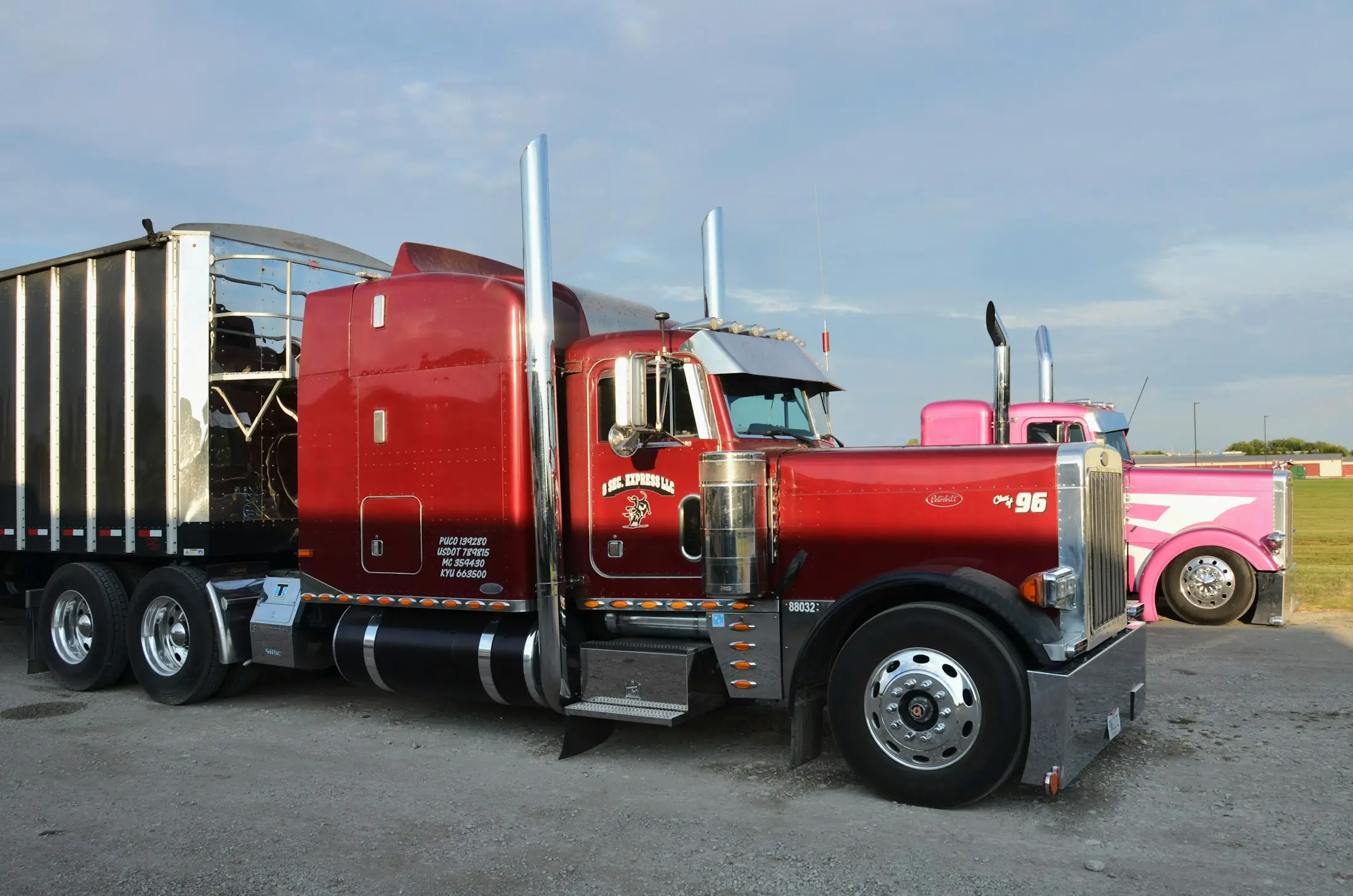 Red Peterbilt tractor parked beside a pink show truck